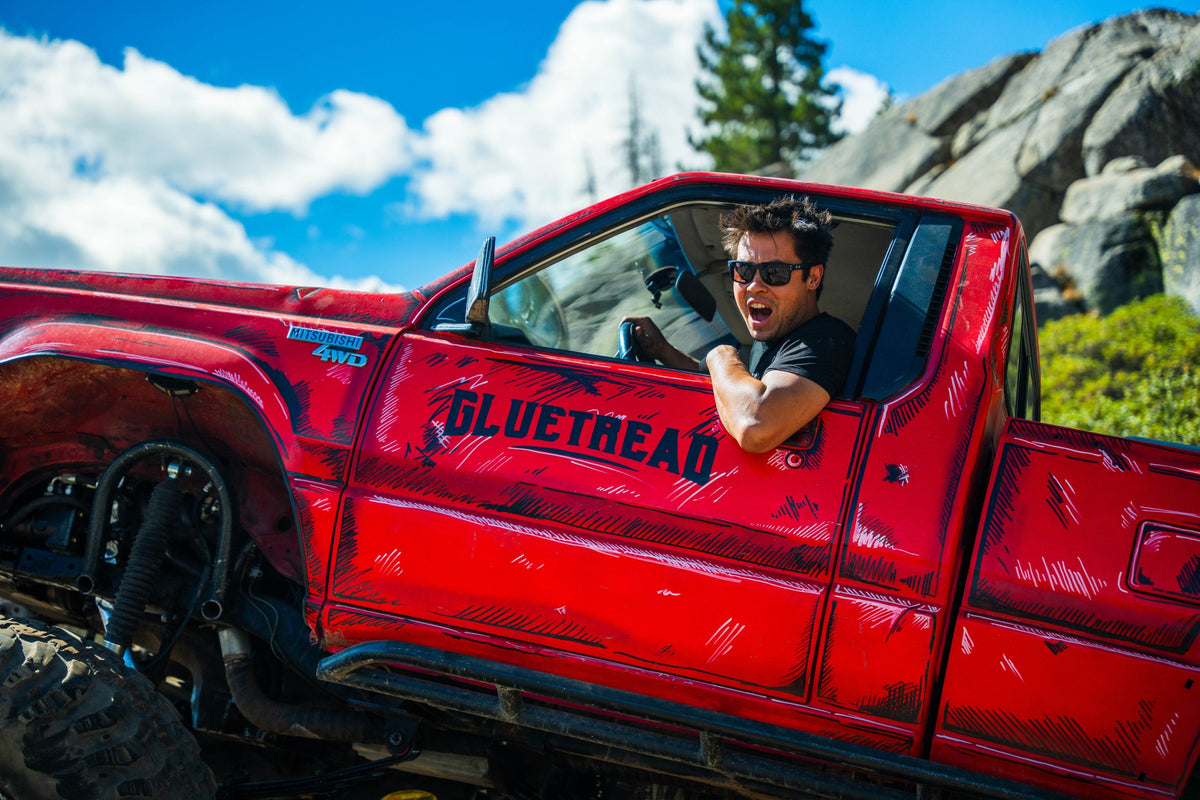 Driver smiling from the window of the GlueTread-branded truck on the Rubicon
