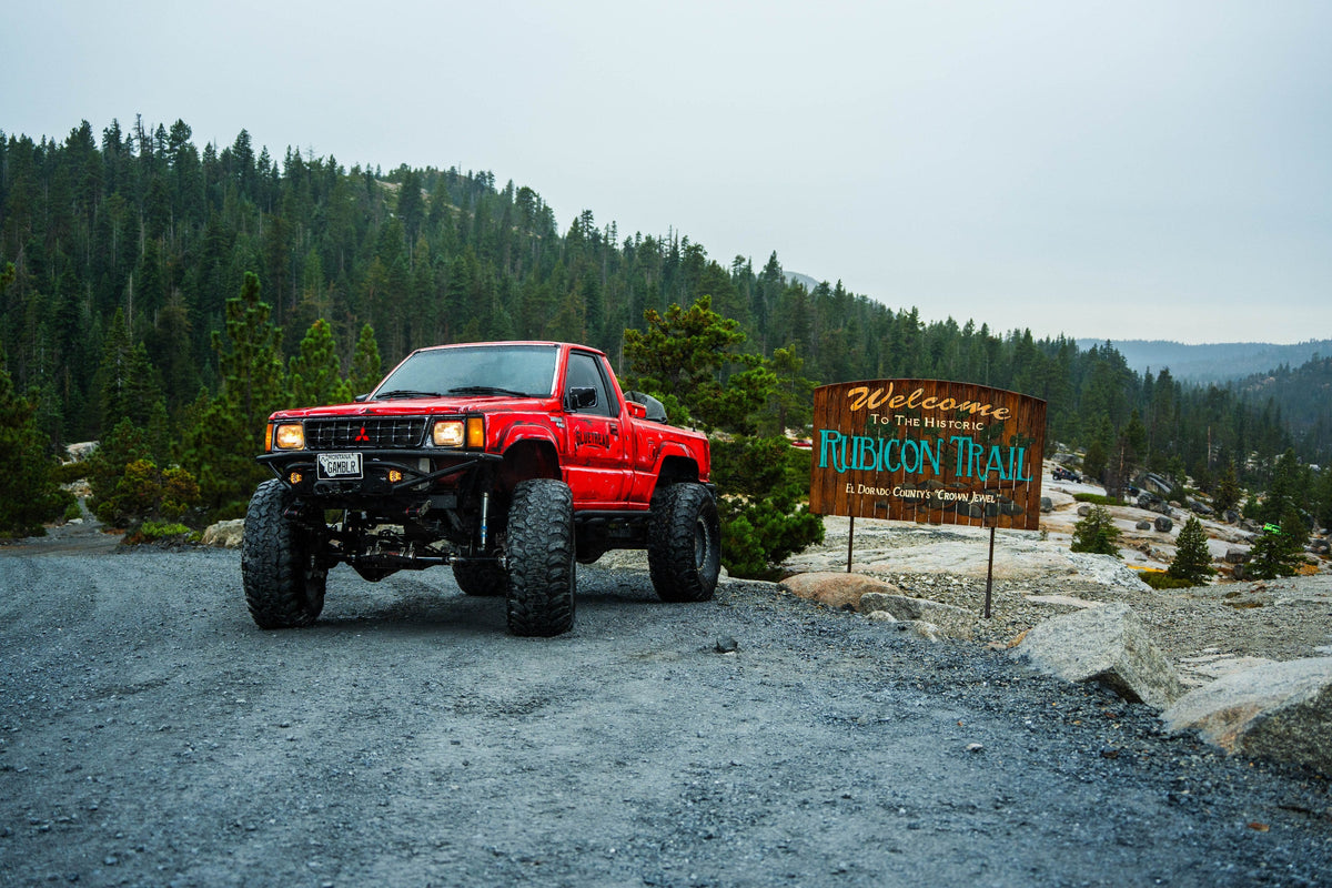 GlueTread-branded red pickup at the Rubicon Trail welcome sign