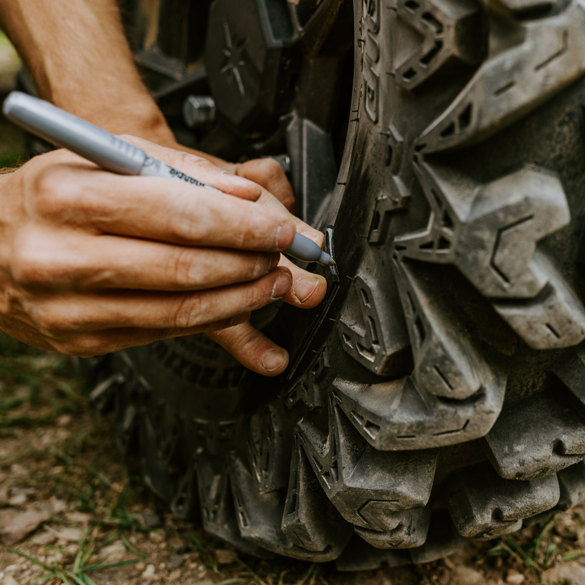 Person marking off-road tire for patch repair